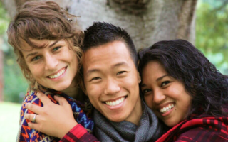 a white female, Asian male, and black female are hugging each other